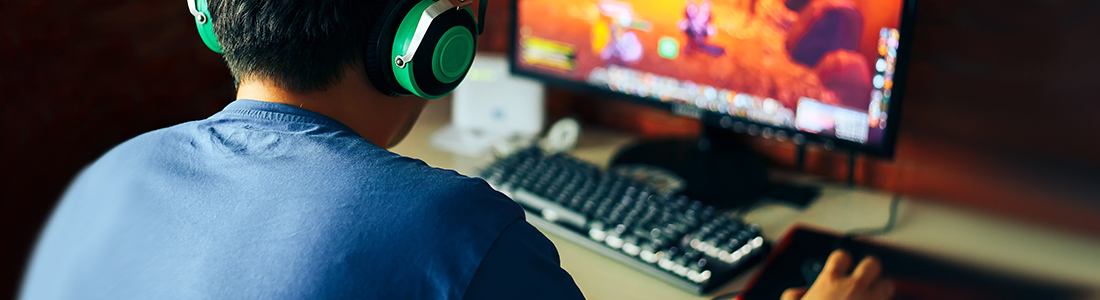 Boy with green headphones in front of playing game screen